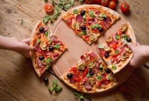 hands taking slices of pizza